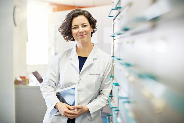 A medical staff wearing a white gown smiling