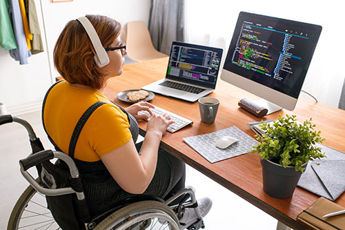A woman sitting at her office in a wheelchair while coding